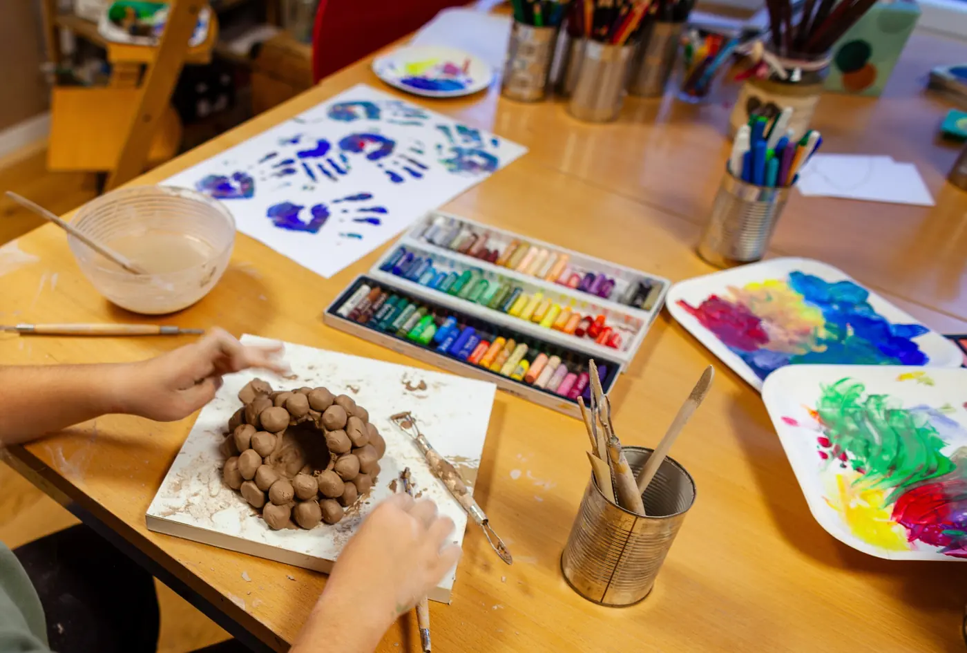 Table de création d'un enfant à l'atelier : peintures, pastels et argile